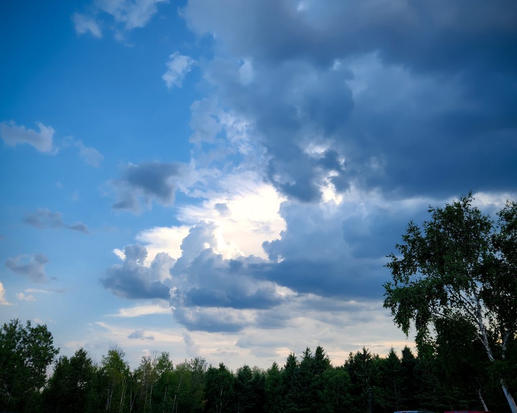 Clouds in the sky suggest a storm approaching. The clouds seem to form an enormous cave in the sky with bright sunlight emanating from it.