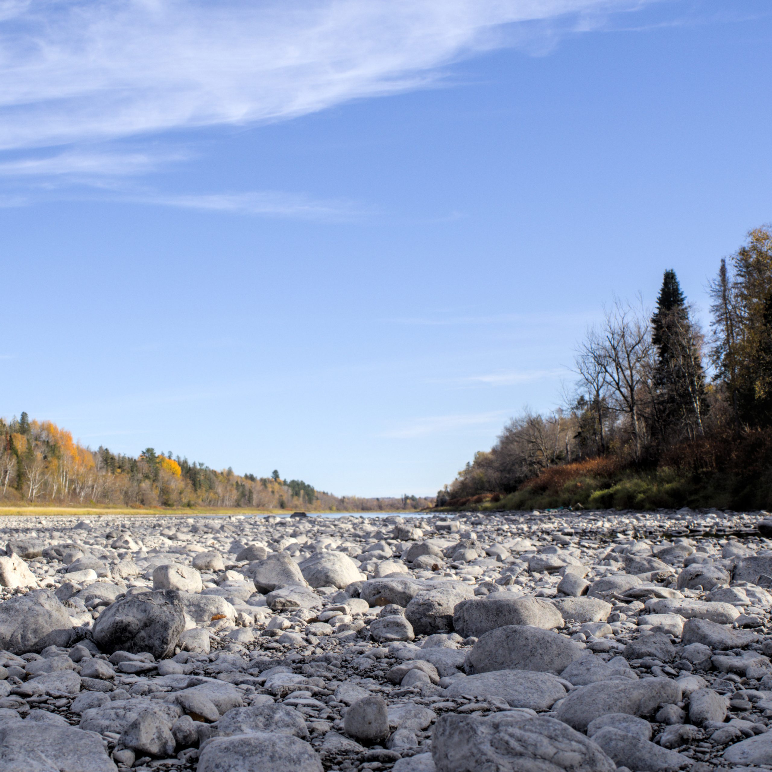 Looking east along the bed of the Aroostook River in Caribou, Maine. The water is quite low and much of the river bed is exposed.
