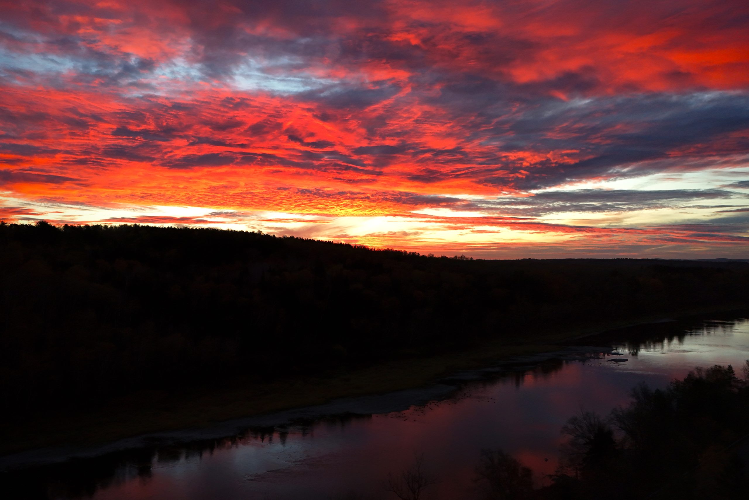 The sky is a mix of blood red and blaze orange as the sun rises over the banks of the Aroostook River in Caribou, Maine.