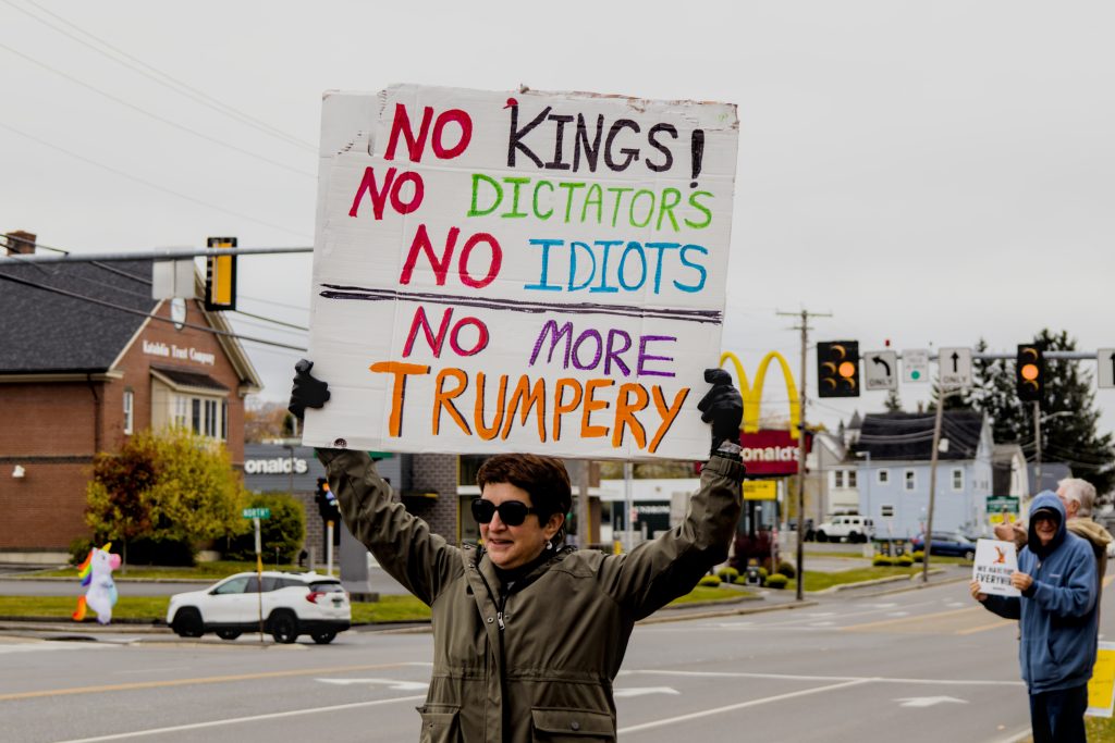 A protester displays a sign that reads "NO KINGS! NO DICTATORS! NO IDIOTS! NO MORE TRUMPERY!" at the No Kings protest in Presque Isle, Maine, on October 18th, 2025.