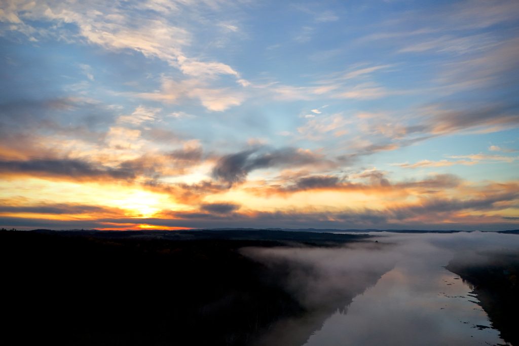The sun rises over Caribou, Maine, and a layer of fog hangs low over the Aroostook River.