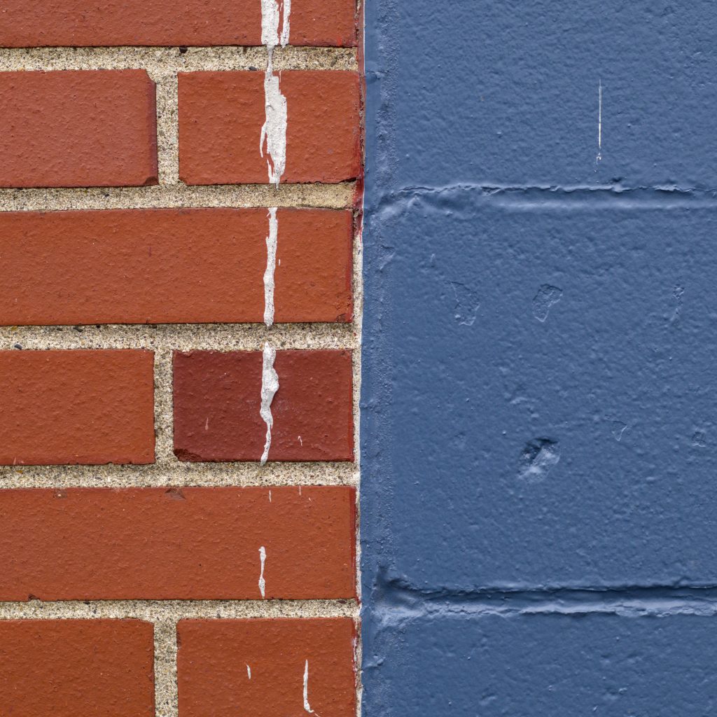 Red brick juxtaposed against cinder block painted blue.