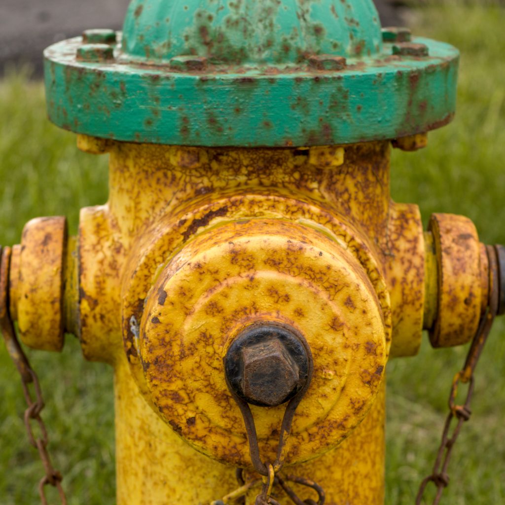 A yellow painted fire hydrant, now spotted with rust.