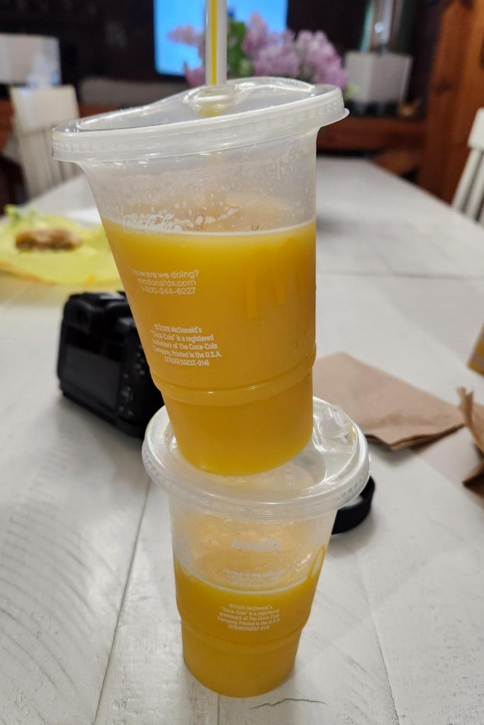 Two McDonalds orange juice cups stacked on top of each other.